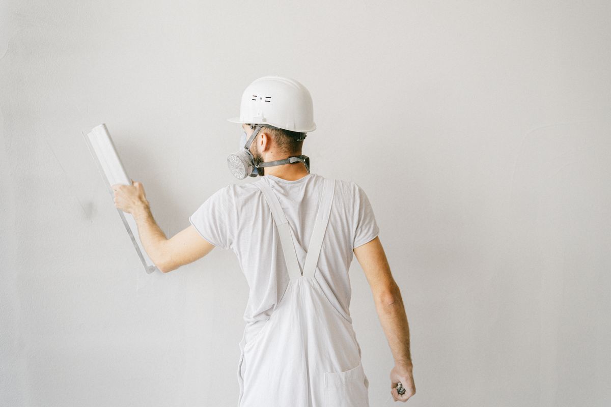 Plasterer in a hard hat smoothing a fresh coat across a wall with a float