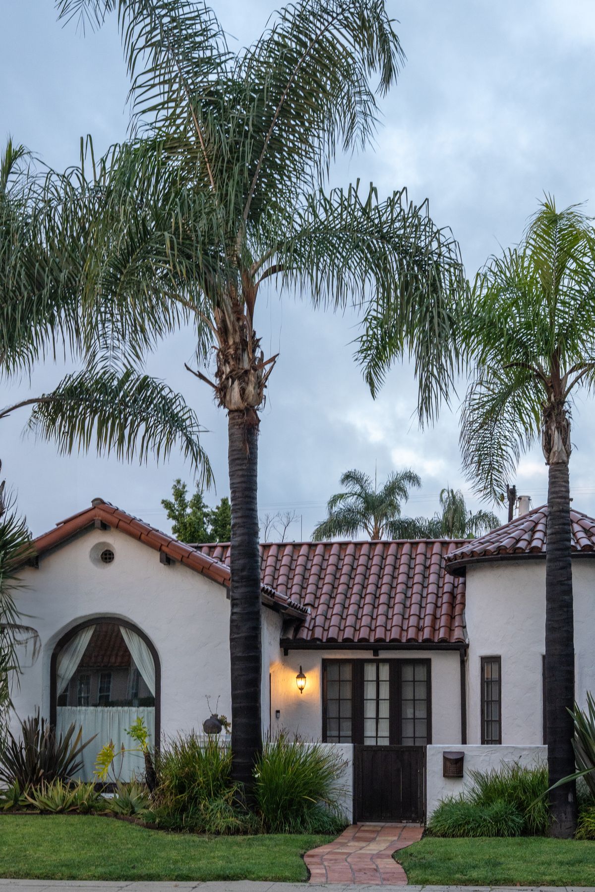 White stucco Spanish-style home with a clay tile roof and palm trees