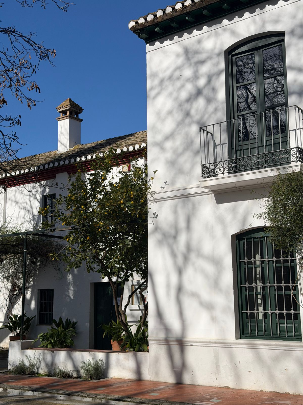 White stucco house with green shutters and an iron balcony